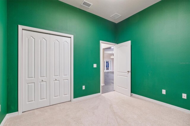 unfurnished bedroom with a closet and light carpet