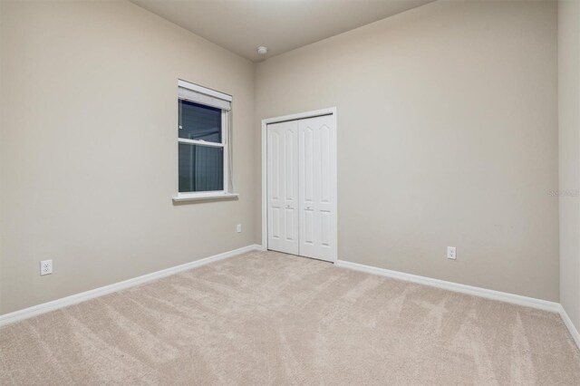 unfurnished bedroom featuring a closet and light carpet