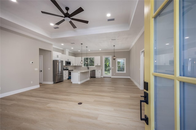 unfurnished living room featuring ceiling fan, crown molding, a tray ceiling, and light hardwood / wood-style flooring