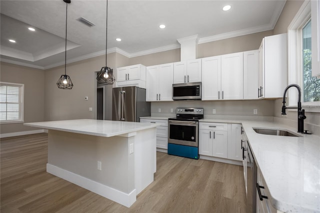 kitchen with appliances with stainless steel finishes, a kitchen island, a healthy amount of sunlight, and sink