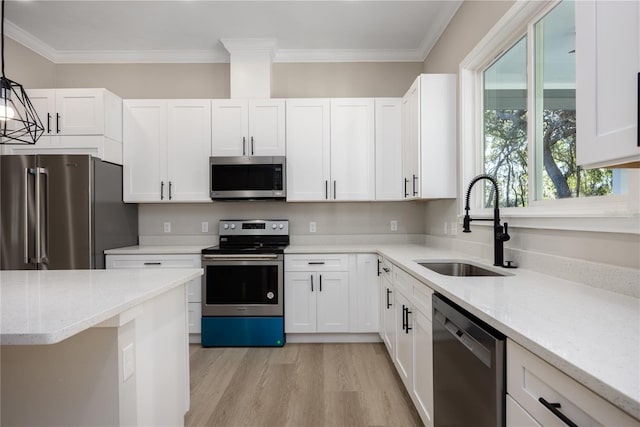 kitchen with pendant lighting, white cabinets, sink, and stainless steel appliances