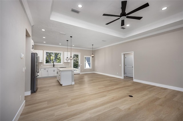 kitchen with pendant lighting, light wood-type flooring, a kitchen island, white cabinetry, and stainless steel refrigerator