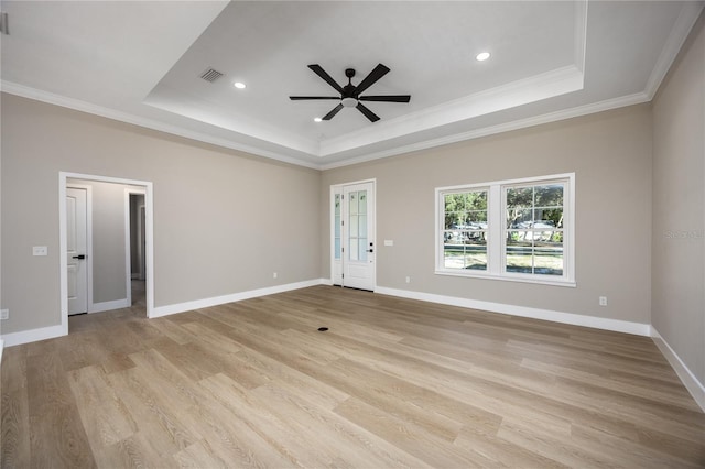 empty room with a tray ceiling, ceiling fan, crown molding, and light wood-type flooring