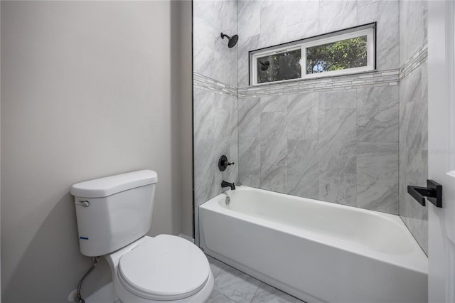 bathroom featuring tiled shower / bath combo and toilet