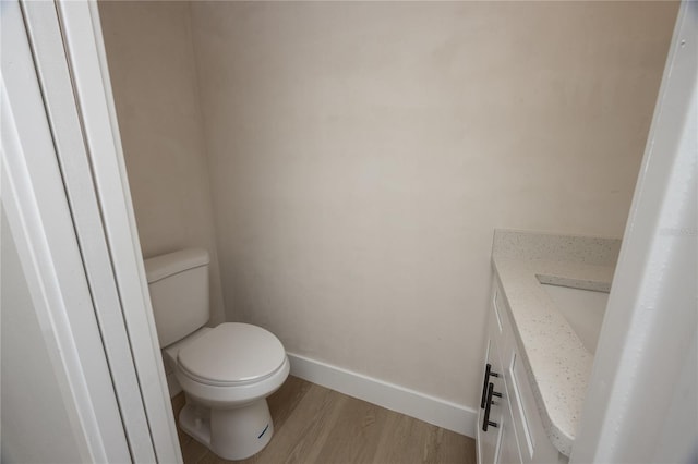 bathroom with hardwood / wood-style floors, vanity, and toilet