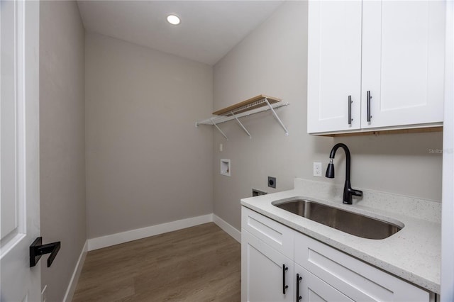 clothes washing area with electric dryer hookup, cabinets, sink, hookup for a washing machine, and light wood-type flooring