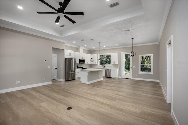 kitchen with pendant lighting, a center island, light wood-type flooring, white cabinetry, and stainless steel appliances