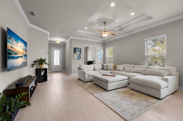 living room featuring crown molding, light hardwood / wood-style flooring, ceiling fan, and a healthy amount of sunlight