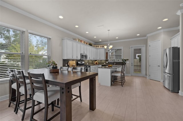 kitchen featuring a kitchen bar, white cabinetry, stainless steel appliances, and decorative light fixtures