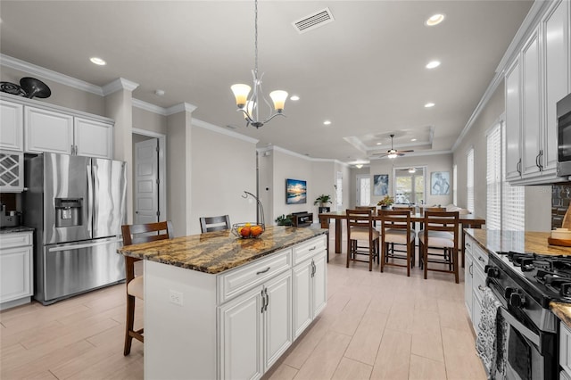 kitchen with a kitchen island, dark stone countertops, stainless steel fridge with ice dispenser, white cabinetry, and a breakfast bar area