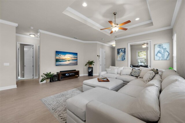 1237 NW 137th Way, Newberry, FL 32669 - living room featuring ceiling fan, a tray ceiling, light wood-type flooring, crown molding, and baseboards