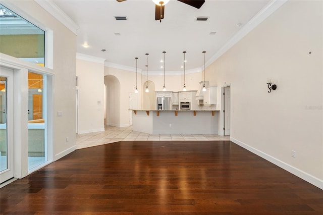 unfurnished living room featuring light wood-type flooring, ceiling fan, and crown molding