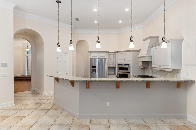 kitchen featuring stainless steel appliances, hanging light fixtures, tasteful backsplash, ornamental molding, and a kitchen breakfast bar