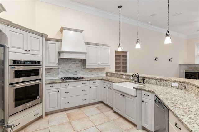 kitchen with white cabinetry, custom range hood, stainless steel appliances, and decorative light fixtures