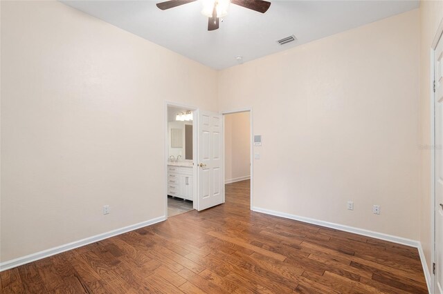 unfurnished bedroom with hardwood / wood-style floors, ceiling fan, and ensuite bath