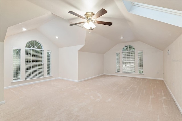 additional living space with light carpet, ceiling fan, and vaulted ceiling with skylight