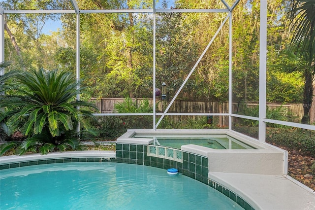 view of swimming pool featuring glass enclosure and an in ground hot tub