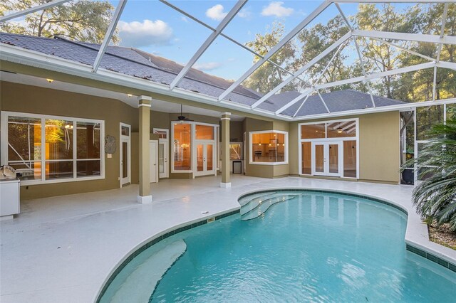 view of pool featuring ceiling fan, glass enclosure, and a patio area