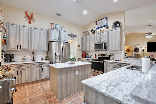 kitchen with a center island, vaulted ceiling, backsplash, and stainless steel appliances