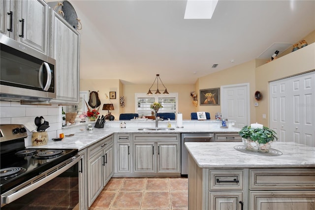 kitchen featuring kitchen peninsula, appliances with stainless steel finishes, sink, and light stone counters