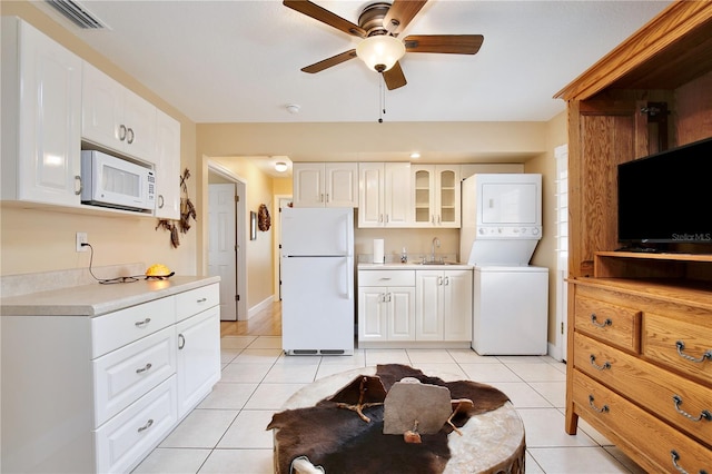 kitchen featuring sink, light tile patterned floors, white appliances, white cabinets, and stacked washer and dryer