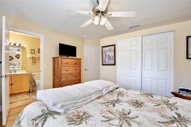 bedroom featuring light hardwood / wood-style floors, ceiling fan, ensuite bath, and a closet