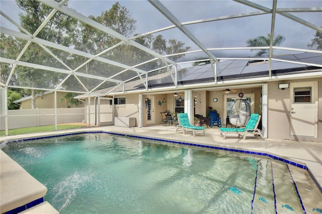 view of swimming pool featuring ceiling fan, glass enclosure, and a patio area