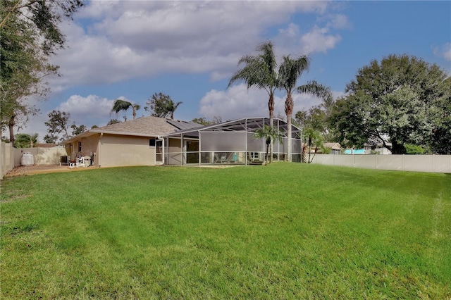 back of house featuring glass enclosure and a yard