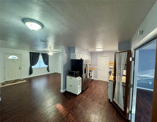 unfurnished living room featuring a textured ceiling, dark wood-style floors, baseboards, and ceiling fan
