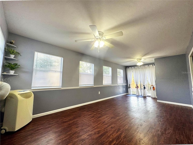 empty room with wood finished floors, a ceiling fan, baseboards, and a textured ceiling