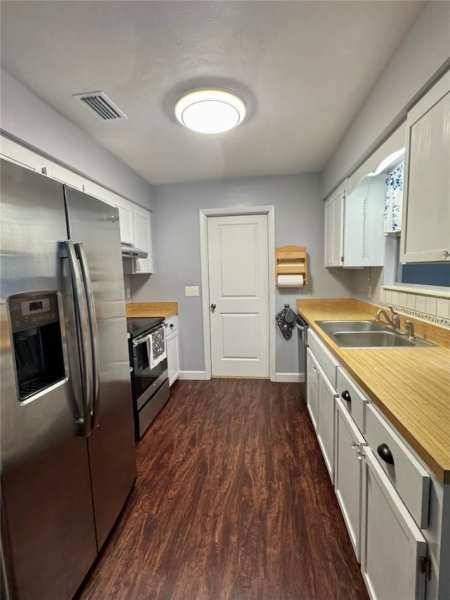 kitchen with stainless steel appliances, a sink, dark wood finished floors, baseboards, and light countertops