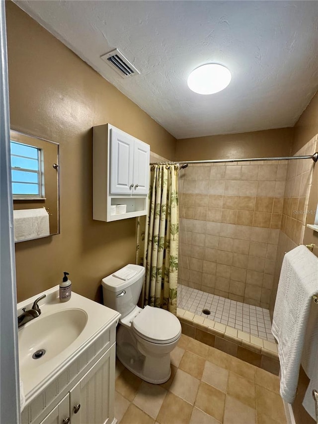 bathroom featuring a stall shower, toilet, vanity, tile patterned flooring, and a textured ceiling