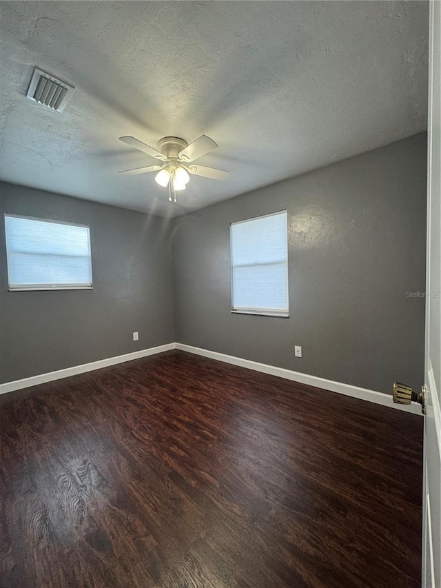 unfurnished room featuring wood finished floors, a textured ceiling, ceiling fan, healthy amount of natural light, and baseboards