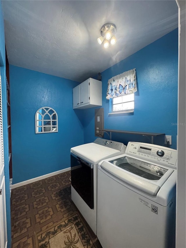 washroom with cabinet space, washer and dryer, baseboards, and electric panel