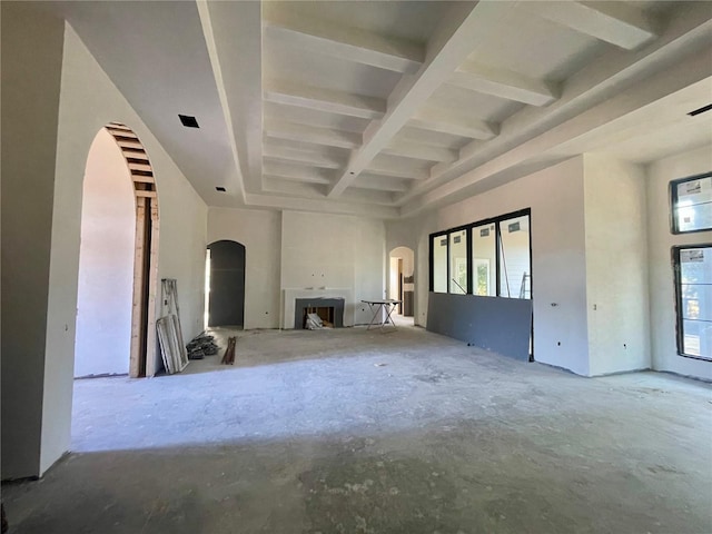 unfurnished living room with a high ceiling, coffered ceiling, and beam ceiling