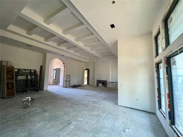 unfurnished living room featuring a high ceiling and beam ceiling