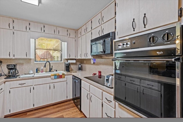 kitchen with light hardwood / wood-style flooring, black appliances, and sink