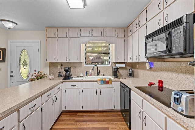 kitchen with black appliances, backsplash, sink, and light hardwood / wood-style floors