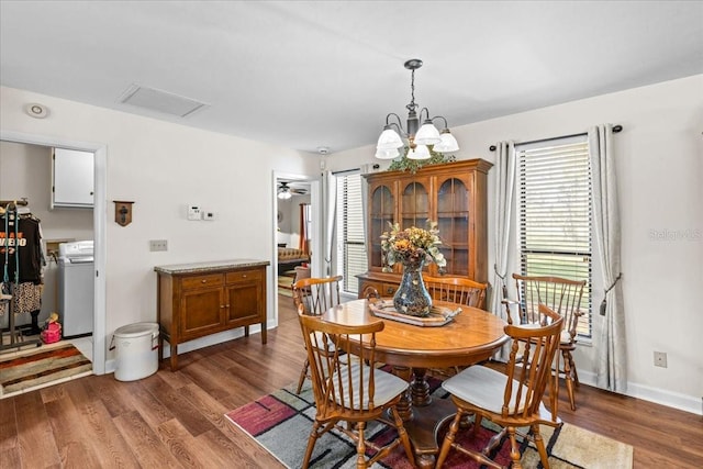 dining space with washer / dryer, a chandelier, and dark hardwood / wood-style flooring