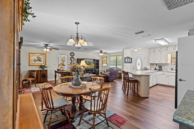 dining area featuring hardwood / wood-style floors and ceiling fan with notable chandelier