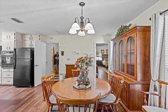 dining area featuring light hardwood / wood-style floors and a chandelier