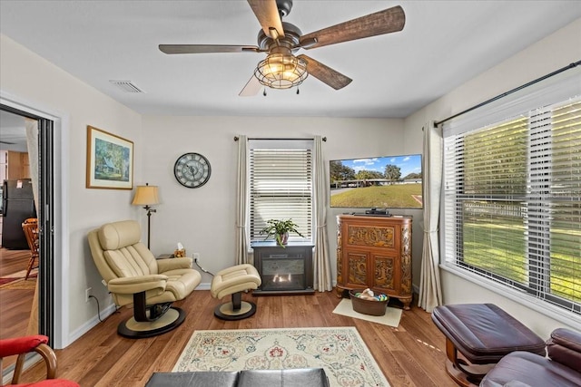 living area with ceiling fan, plenty of natural light, and light wood-type flooring