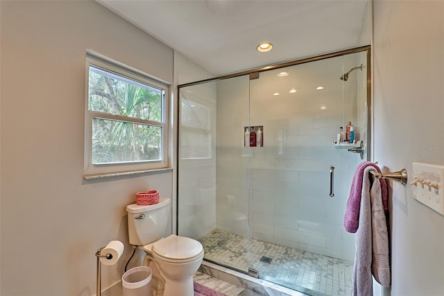 bathroom featuring toilet and a shower with shower door