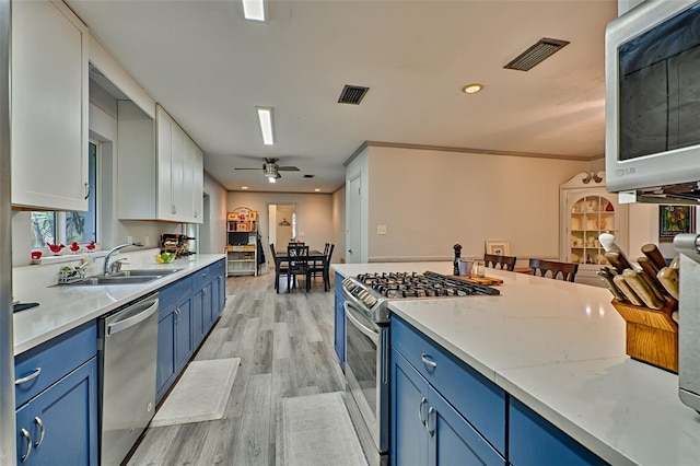 kitchen with stainless steel appliances, white cabinetry, sink, ceiling fan, and light wood-type flooring