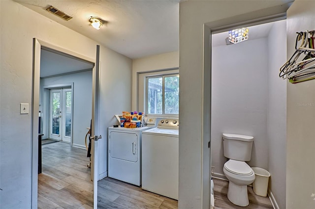 clothes washing area with light wood-type flooring and washer and clothes dryer