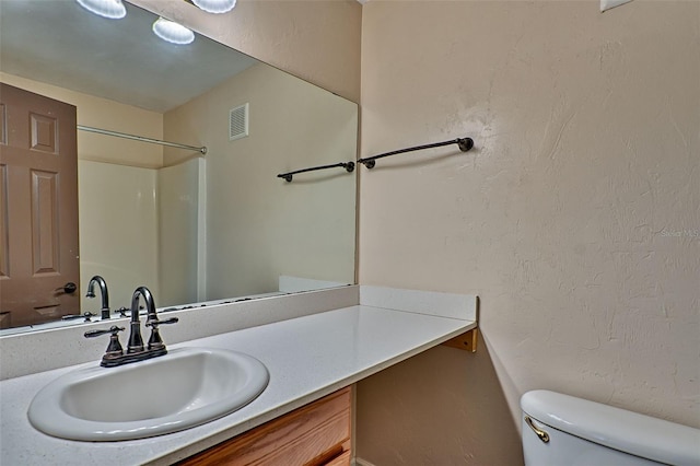 bathroom featuring walk in shower, vanity, and toilet