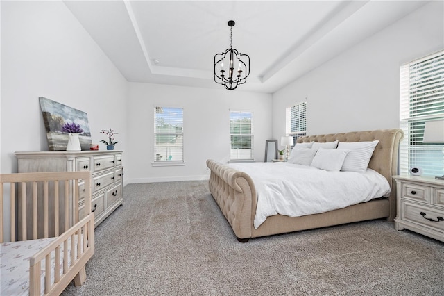 carpeted bedroom featuring a tray ceiling and a notable chandelier