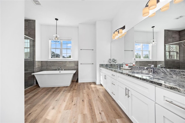 bathroom featuring vanity, independent shower and bath, tile walls, and hardwood / wood-style flooring