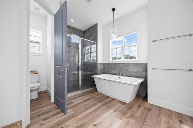 bathroom with hardwood / wood-style floors, toilet, plus walk in shower, and tile walls