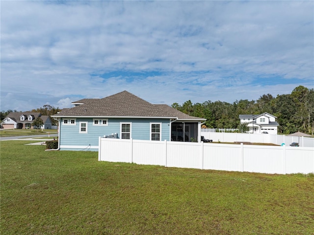 rear view of house featuring a sunroom and a lawn